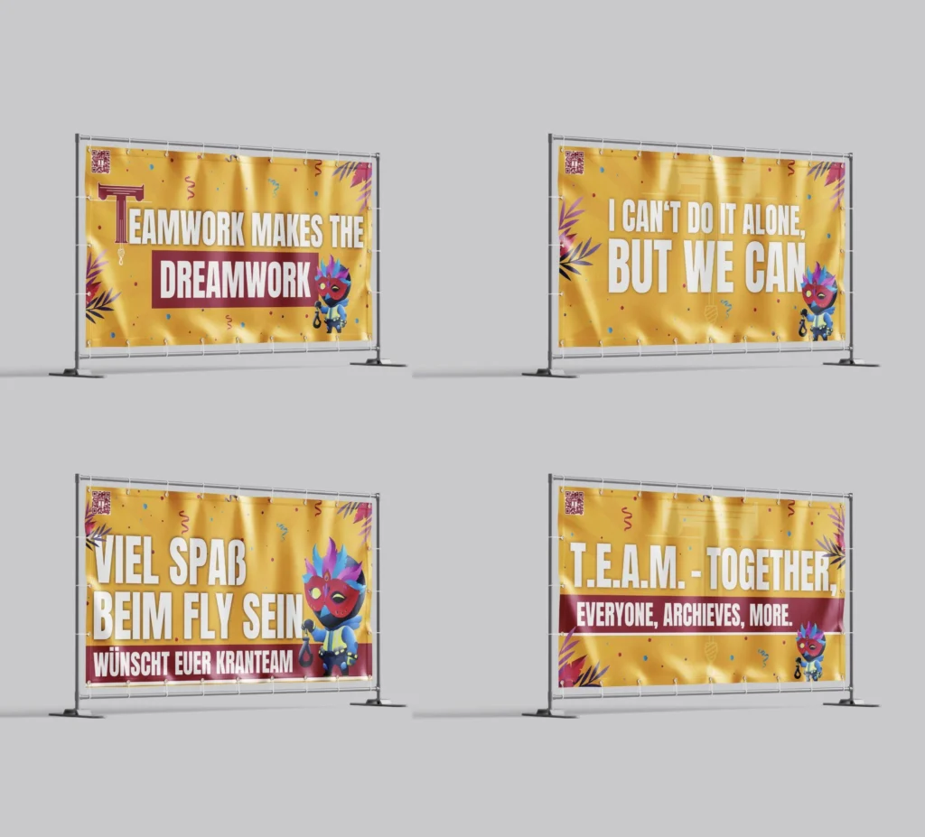 Vier gelb-orange Banner auf Metallzaunrahmen zeigen große Team-Sprüche und kleine farbige Gestaltungselemente.