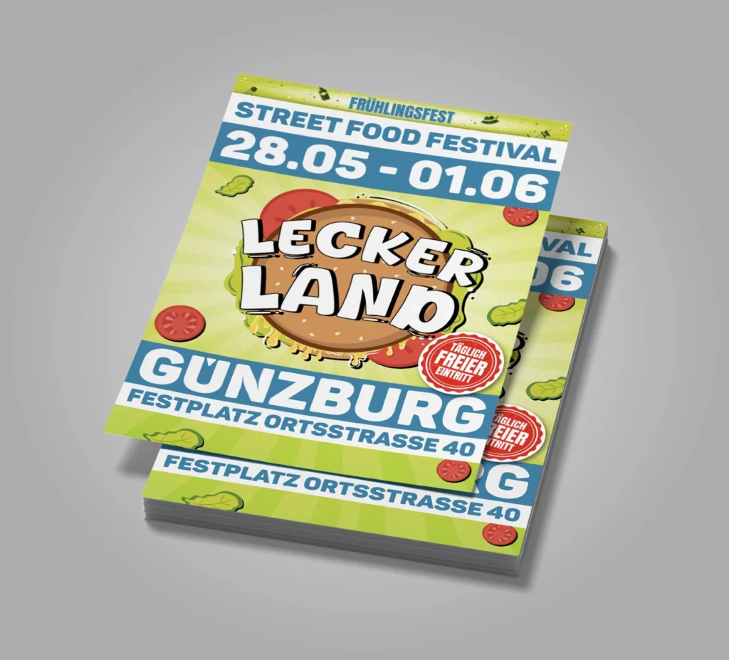Zwei gelb-grüne Flyer mit Burgerillustration und „Lecker Land“-Aufschrift sind gestapelt vor grauem Hintergrund dargestellt.